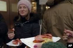 Customers eat hot sausages at a traditional sausage stand (Wuerstelstand), which are named as intangible cultural heritage by the Austrian UNESCO Commission, in Vienna, Austria, Thursday, Nov. 28, 2024. (AP Photo/Heinz-Peter Bader)