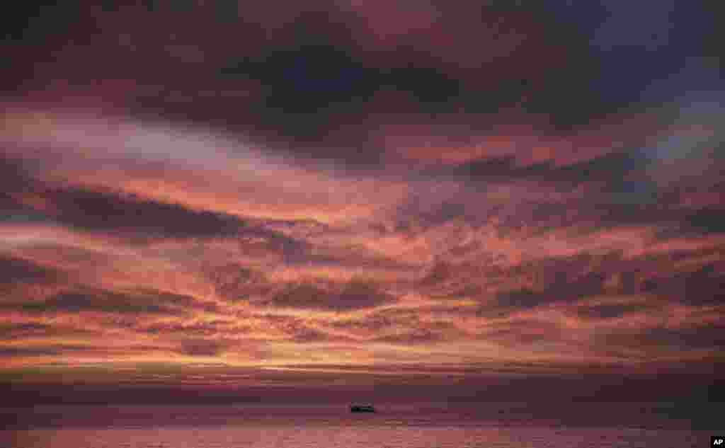 A Palestinian fishing boat sails as the sun sets on the coast off Gaza City, March 18, 2018.