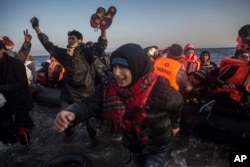 Refugees and migrants react as they disembark from a dinghy after their arrival from the Turkish coast to the northeastern Greek island of Lesbos on Nov. 17, 2015.