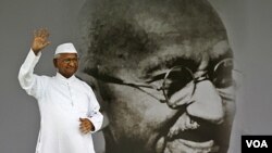 Aktivis Anna Hazare dengan latar belakang gambar Mahatma Gandhi di New Delhi. Gerakan anti-korupsi damai yang dipimpin Anna Hazare mendapatkan simpati dari rakyat semua kalangan dan kelompok usia di India.