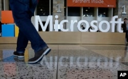 FILE - In this April 28, 2015 file photo, a man walks past a Microsoft sign set up for the Microsoft BUILD conference at Moscone Center in San Francisco.