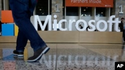 ຊາຍຄົນນຶ່ງຢ່າງຜ່ານປ້າຍບໍລິສັດ Microsoft ທີ່ຕັ້ງສຳລັບ ກອງປະຊຸມ Microsoft BUILD ທີ່ສູນກາງ Moscone ໃນນະຄອນ San Francisco ວັນທີ 28 ເມສາ 2015. 