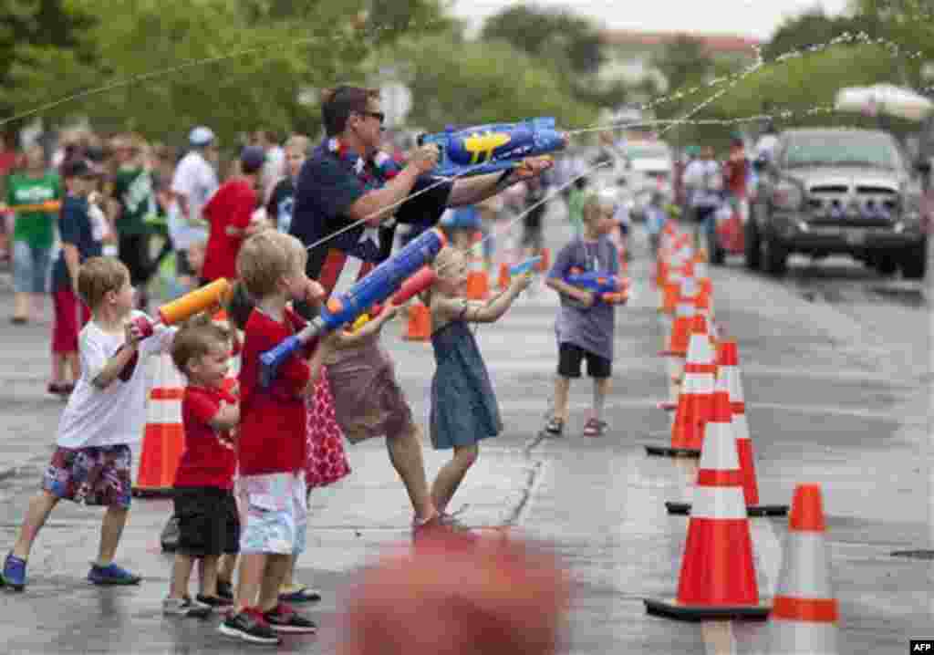 Spectators lining Nevada Way shoot water guns at passing floats during the 63rd Annual Boulder City Damboree Parade, Monday, July 4, 2011, in Boulder City, Nev. The last half of the parade entrants are called Water Entrees, making them fair game for water