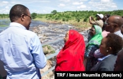 FILE - Tanzanian Vice President Samia Suluhu Hassan, in the red shawl, is briefed about the destruction of the Ruaha river, in Kilolo district, Tanzania, May 8, 2017.
