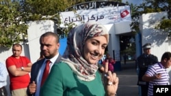 Soumaya Rached Ghannouchi shows her ink-stained finger after voting in the country's first post-revolution parliamentary election on October 26, 2014 in the Tunis suburb of Ben Arous.