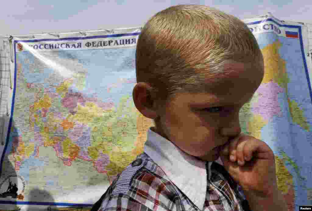 A boy stands in front of a map of Russia at a refugee camp set up for Ukrainian refugees, outside Donetsk, Aug. 18, 2014.&nbsp;