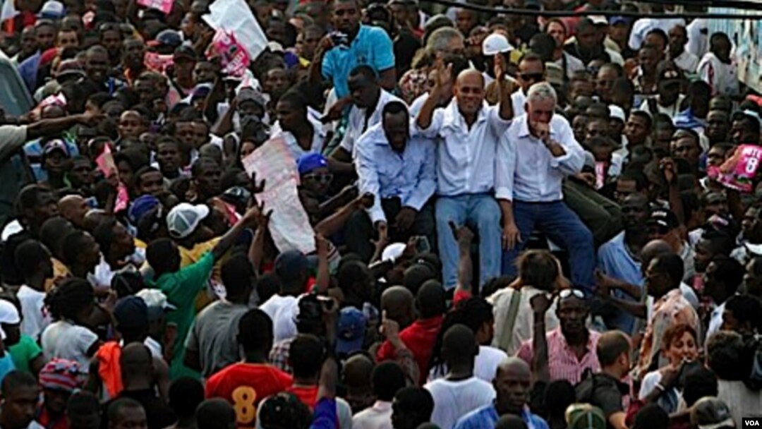 Kandidat presiden Haiti, Michel Martelly (tengah) ditemani kandidat lainnya, Charles-Henri Baker (kanan) dan musisi Wyclef Jean naik ke atas kendaraan yang berjalan melintasi jalanan kota Port-au-Prince untuk memrotes pemilu.