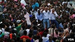 Kandidat presiden Haiti, Michel Martelly (tengah) ditemani kandidat lainnya, Charles-Henri Baker (kanan) dan musisi Wyclef Jean naik ke atas kendaraan yang berjalan melintasi jalanan kota Port-au-Prince untuk memrotes pemilu.