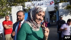 FILE – A voter shows her ink-stained finger after participating in Tunisia’s first post-revolution parliamentary election in the Tunis suburb of Ben Arous, Oct. 26, 2014.