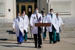 Dr. Sean Conley, physician to President Donald Trump, center, and other doctors, walk out to talk with reporters at Walter Reed National Military Medical Center in Bethesda, Md., Oct. 5, 2020.