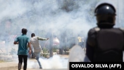 Manifestante pontapeia uma lata de gás lacrimogéneo atirada por polícias durante a manifestação anti-governo, em Luanda, 11 novembro 2020