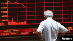 An investor watches an electronic board showing stock information at a brokerage office in Beijing, China, July 7, 2015.