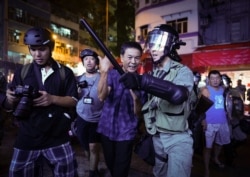 A Pro-China supporter, center, is escorted by police after confronting journalists in north point, Hong Kong, Sept. 15, 2019.
