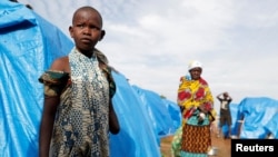 FILE - A girl who had part of her arm chopped off by militiamen when they attacked her village of Tchee, stands in a camp for internally displaced people in Bunia, Ituri province, Democratic Republic of Congo, April 12, 2018.