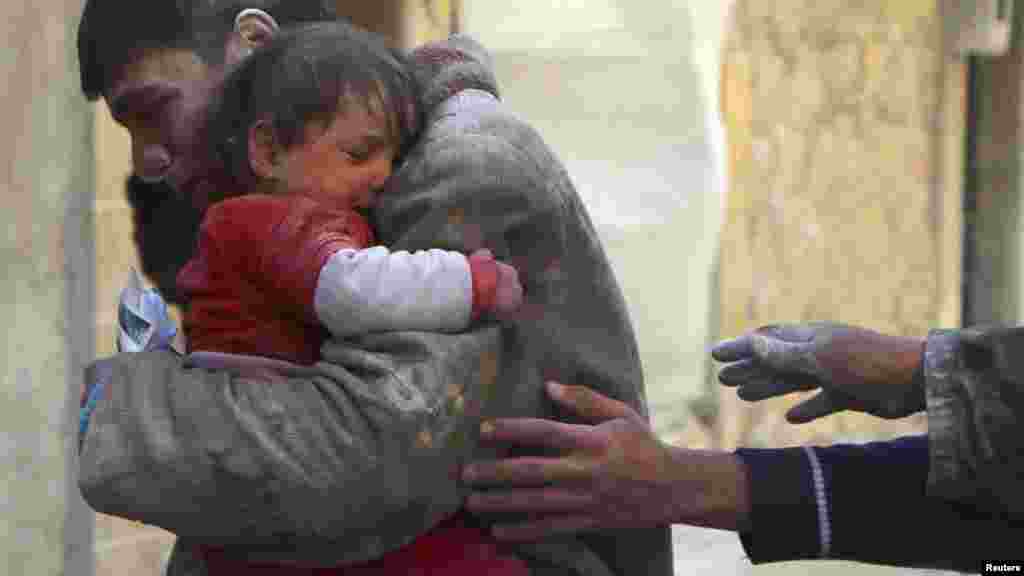 A boy holds his baby sister, who survived what activists say was an airstrike by forces loyal to Syrian President Bashar al-Assad in Aleppo, Feb. 14, 2014.
