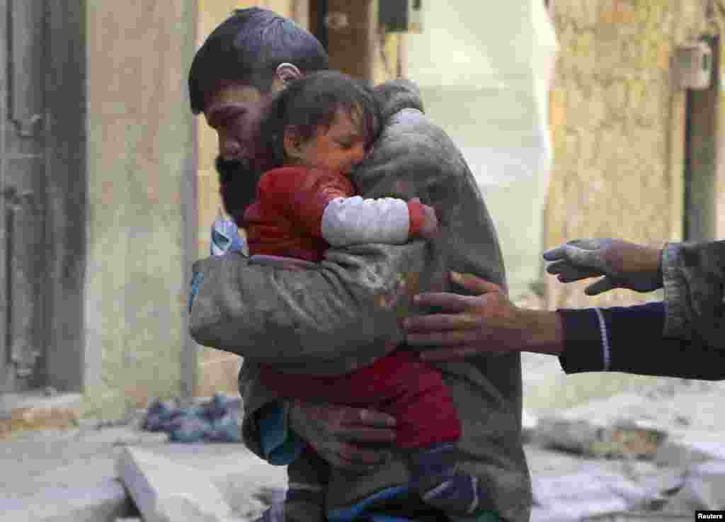 پسری جوان خواهر کوچکش را در آغوش گرفته که از حمله هوایی نیروهای وابسته به حاکمیت سوریه جان سالم به دربرده است. حلب - ۱۴ فوریه
