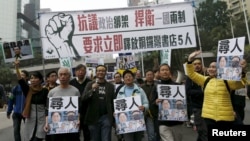 FILE - Demonstrators hold up portraits of five missing staff members of a publishing house and a bookstore during a protest over the disappearance of booksellers in Hong Kong, Jan. 10, 2016. 