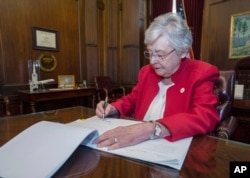 This photograph released by the state shows Alabama Gov. Kay Ivey signing a bill that virtually outlaws abortion in the state, May 15, 2019, in Montgomery, Ala.