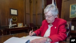 This photograph released by the state shows Alabama Gov. Kay Ivey signing a bill that virtually outlaws abortion in the state, May 15, 2019, in Montgomery, Ala.