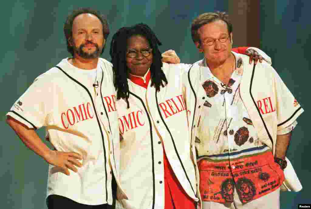 Comedians Robin Williams (R), Billy Crystal (L) and Whoopi Goldberg share a hug on the stage of New York's Radio City Music Hall at the end of HBO's "Comic Relief 8" show, June 14, 1998. 