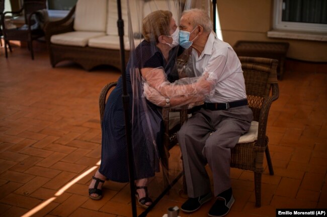 Pasangan lain: Agustina Canamero, 81 tahun, dan Pascual Perez, 84 tahun terpaksa berciuman dibatasi oleh plastik di panti jompo di Barcelona, di tengah pandemi COVID-19 di Spanyol (foto: dok).