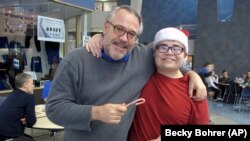 Alaska City Kindness Campaign - In this Dec. 20, 2016 photo, Thunder Mountain High School Principal Dan Larson, left, poses for photos with Mitchell Henderson, one of the students from Juneau-Douglas High School.