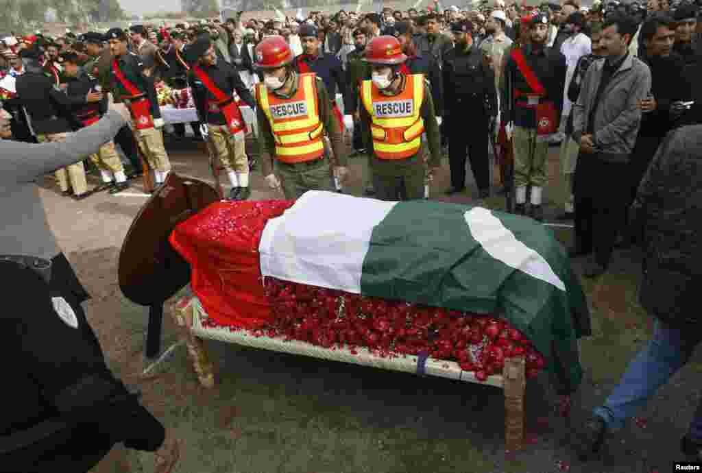 People gather around the coffin of the provincial minister for local government Bashir Ahmad Bilour, who died of his wounds from a bombing attack, during his funeral at the Army Stadium in Peshawar December 23, 2012. Taliban Islamic militants bombed a pol