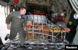 U.S. Coast Guard Petty Officers Nicholas Eudier, left, and Nate Matthews unload relief supplies for Hurricane Dorian victims from their C-130 aircraft in Andros, Bahamas, Sept. 7, 2019.