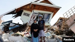 Darmi dan adik lelakinya, Rusli, berdiri di depan rumah mereka di Balaroa, Sulawesi Tengah.