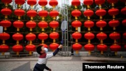 Seorang anak laki-laki mengenakan masker bermain bulu tangkis di jalan yang dihias untuk perayaan Tahun Baru Imlek, menyusul wabah COVID-19 di Wuhan. (Foto: Reuters)