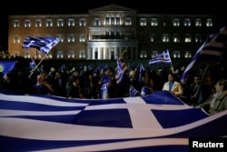 Protesters hold a giant Greek national flag during a demonstration against the agreement reached by Greece and Macedonia to resolve a dispute over the former Yugoslav republic's name, in front of the parliament building in Athens, Greece, Jan. 24, 2019.