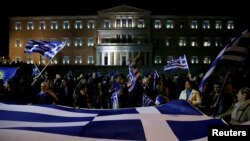 FILE - Protesters hold a giant Greek national flag during a demonstration against the agreement reached by Greece and Macedonia to resolve a dispute over the former Yugoslav republic's name, in front of the parliament building in Athens, Jan. 24, 2019.