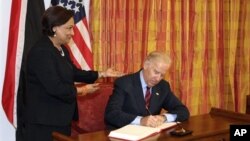 Vice President Biden, signs the guest book as Trinidad & Tobago's Prime Minister Kamla Persad-Bissessar looks on in St. Anns, Trinidad. May 28, 2013. (AP Photo)