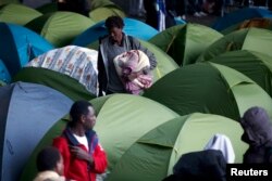 With police present, social workers evacuate migrants from a tent camp under the Charles de Gaulle Bridge along the Seine in southeast Paris, Sept. 17, 2015.