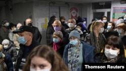 People wearing protective face masks wait in a queue at a clinic in Omsk