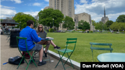 Students work on their computers on a lawn at the University of Pittsburgh in May 2021.