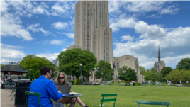 Sam Kelly and Kelly Schanes work outside at the University of Pittsburgh. They recently attend their school's graduation ceremony at a professional baseball stadium.