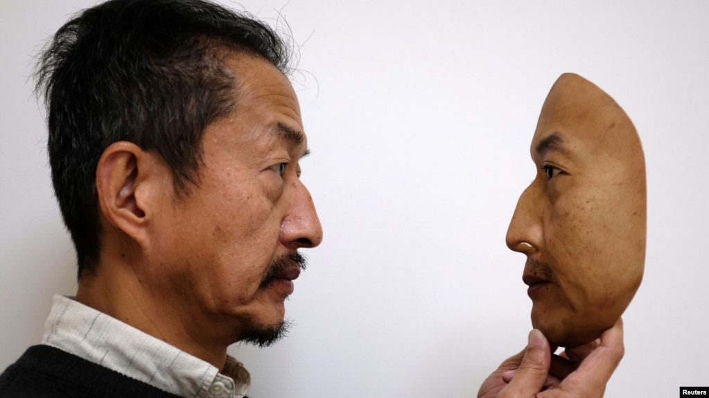 REAL-f Co. President Osamu Kitagawa holds a super-realistic face mask at his factory in Otsu, western Japan, Nov. 15, 2018. 