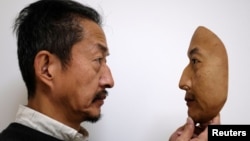 REAL-f Co. President Osamu Kitagawa holds a super-realistic face mask at his factory in Otsu, western Japan, Nov. 15, 2018. 