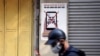 FILE - A man uses a smartphone as he walks past a poster warning against the spread of 'fake news' on the coronavirus, in Hanoi, Vietnam April 14, 2020. 