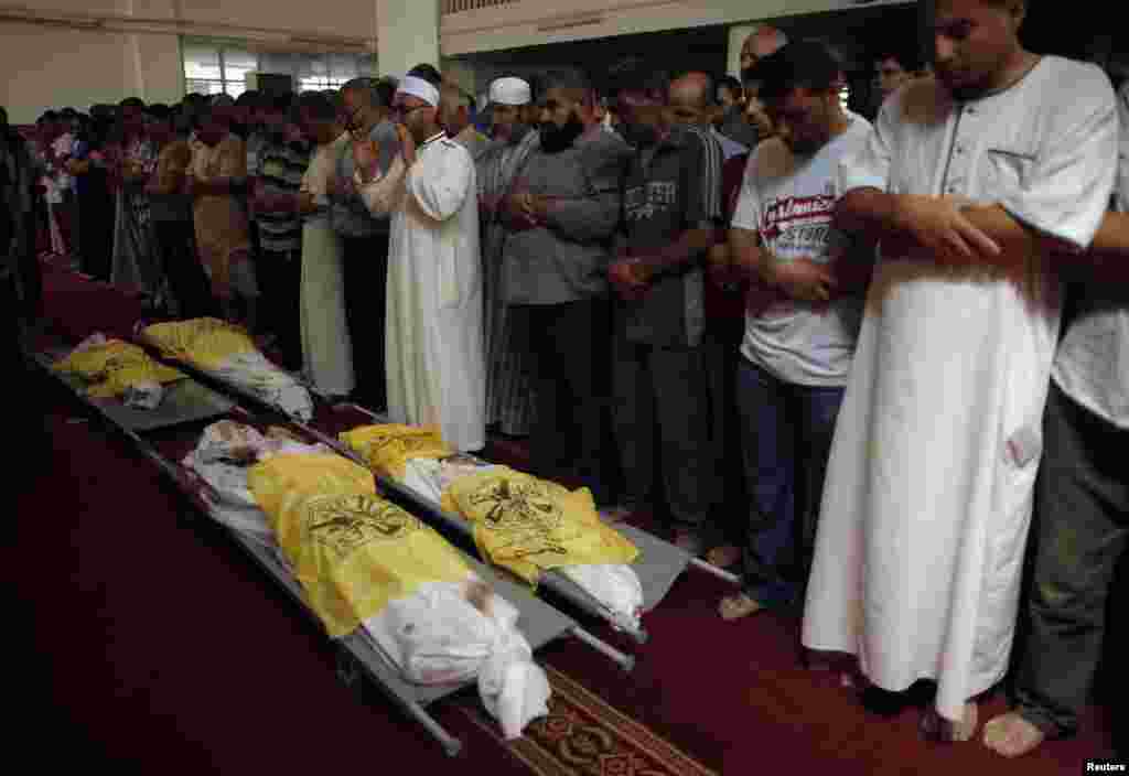 People pray next to the bodies of Palestinians killed in Israeli air strikes during their funeral at a mosque in Gaza City, Aug. 21, 2014.