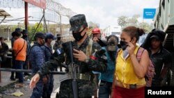 Un oficial de policía de Honduras ayuda a un migrante hondureño que intentaba llegar a Estados Unidos, luego de que las autoridades guatemaltecas los escoltaran de regreso, en la frontera de Corinto entre Guatemala y Honduras.