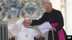 Pope Francis is helped by his personal secretary Mons. Alfred Xuereb, right, with his skull cap during a gust of wind while he attends his weekly open-air general audience in St. Peter's Square at the Vatican, Wednesday, May 22, 2013.