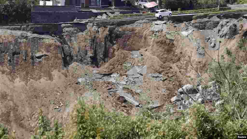 A car hangs on a collapsed road caused by an earthquakes in Minamiaso town, Kumamoto prefecture, in this photo taken by Kyodo, April 16, 2016.