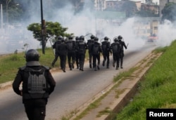 FILE - Ivory Coast riot policemen disperse opposition supporters with tear gas during a march to protest against Ivory Coast's President Alassane Ouattara's new constitution in Abidjan, Ivory Coast, Oct. 20, 2016.