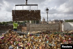 City municipal employees lower iron grills covered with "love locks" into a truck after they were removed from the Pont des Arts in Paris, June 1, 2015.
