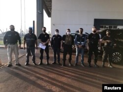 Personnel of the General Directorate of Migration, agents of the Paraguayan office of INTERPOL and members of the Federal Police of Brazil pose for a photo, during the handover of Brazilian citizen Chelbe Willams Moraes in an unknown location, June 7, 2021.