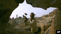 Cambodian It On, 60, holds a hammer for breaking stone used in construction at Phnom Baseth hill, file photo. 