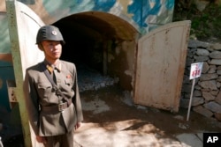 FILE - In this May 24, 2018 photo, a guard stands at the entrance of the north tunnel at North Korea's nuclear test site, which was blown up soon after this photo was made, in a display of dismantling the test site, at Punggye-ri, North Hamgyong Province, North Korea.