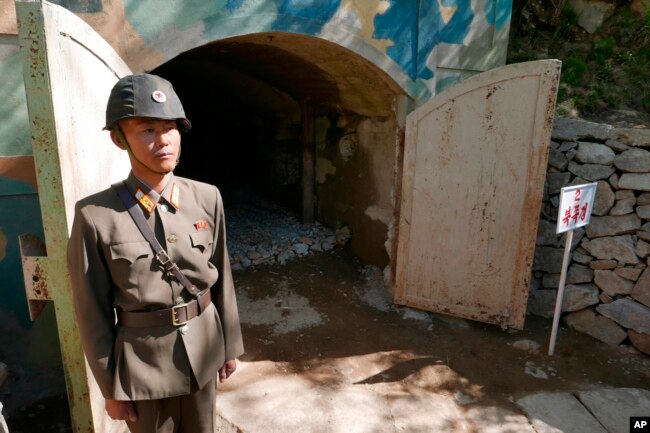 FILE - In this May 24, 2018 photo, a guard stands at the entrance of the north tunnel at North Korea's nuclear test site, which was blown up soon after this photo was made, in a display of dismantling the test site, at Punggye-ri, North Hamgyong Province, North Korea.